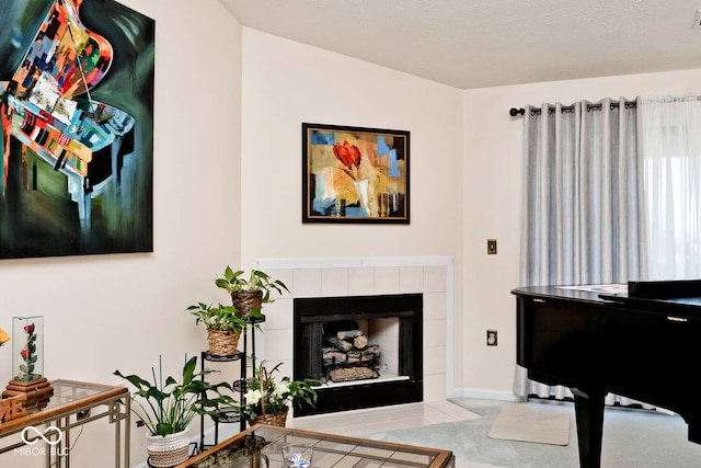 sitting room with a textured ceiling, a tile fireplace, and light colored carpet