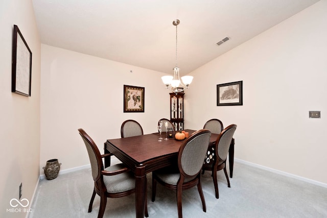 carpeted dining space with vaulted ceiling and a chandelier