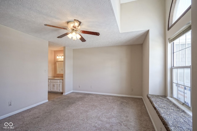 spare room with a ceiling fan, light carpet, a textured ceiling, and baseboards