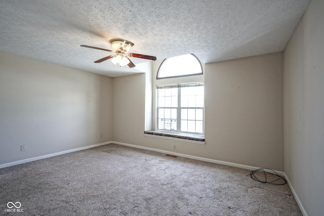 carpeted empty room featuring a textured ceiling, a ceiling fan, and baseboards