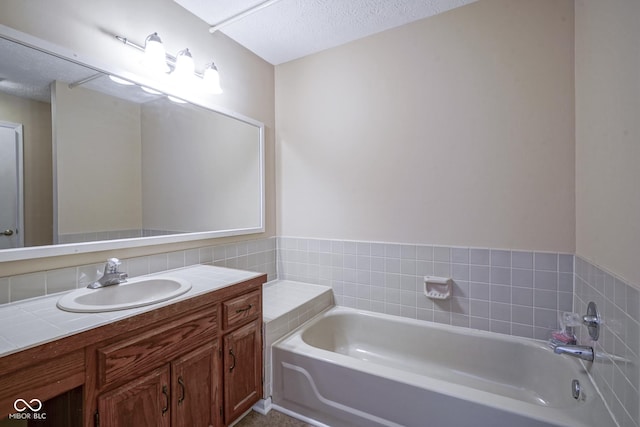 bathroom with a textured ceiling, vanity, and a tub to relax in