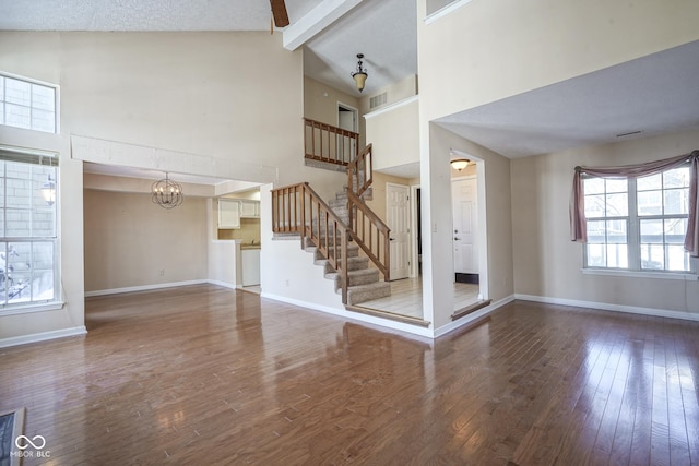 unfurnished living room featuring stairway, beamed ceiling, wood finished floors, and baseboards