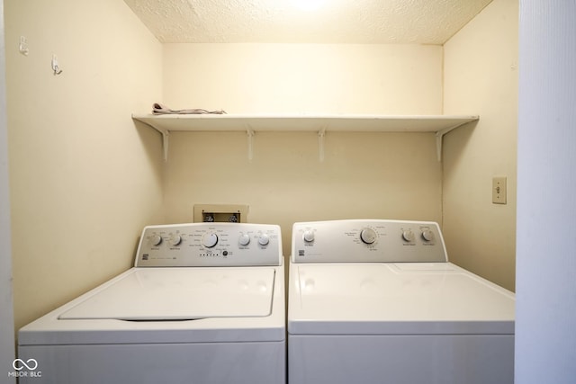 clothes washing area featuring laundry area, a textured ceiling, and washer and dryer