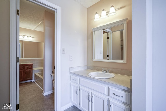 bathroom with a bathing tub, vanity, and a textured ceiling