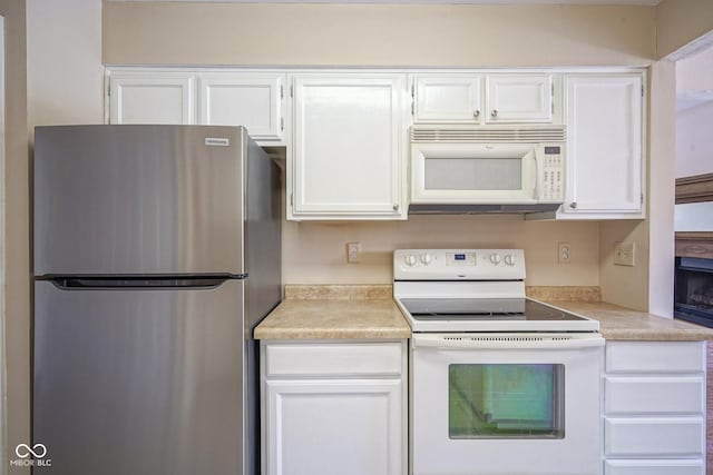 kitchen featuring white appliances, white cabinets, and light countertops