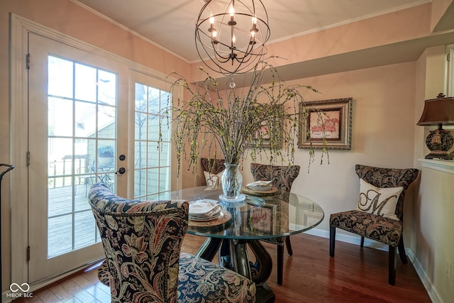 dining space featuring an inviting chandelier, baseboards, crown molding, and wood finished floors