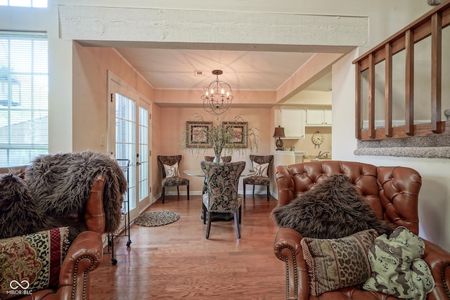 living area with light wood finished floors, baseboards, a chandelier, and crown molding