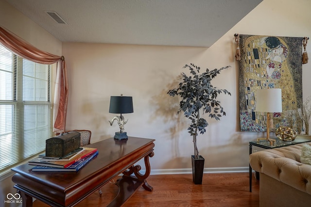 office area featuring a textured ceiling, wood finished floors, visible vents, and baseboards