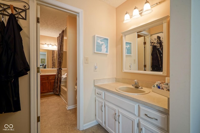 full bathroom featuring baseboards, vanity, and a textured ceiling