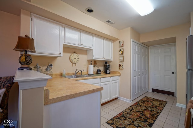 kitchen with a peninsula, a sink, visible vents, white cabinets, and light countertops