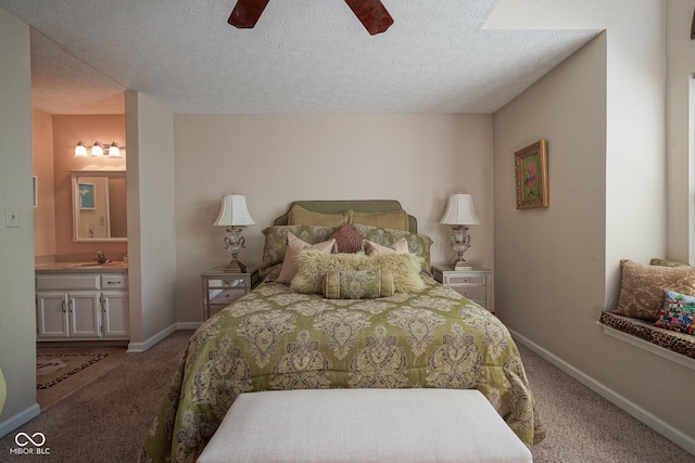 carpeted bedroom featuring a sink, a textured ceiling, ensuite bath, ceiling fan, and baseboards