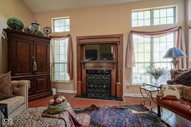 sitting room featuring lofted ceiling, a fireplace with flush hearth, dark wood finished floors, and baseboards