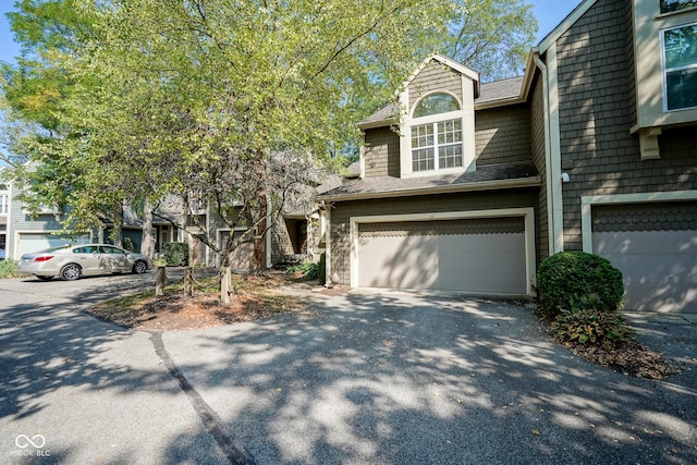 view of front facade with an attached garage, aphalt driveway, and roof with shingles