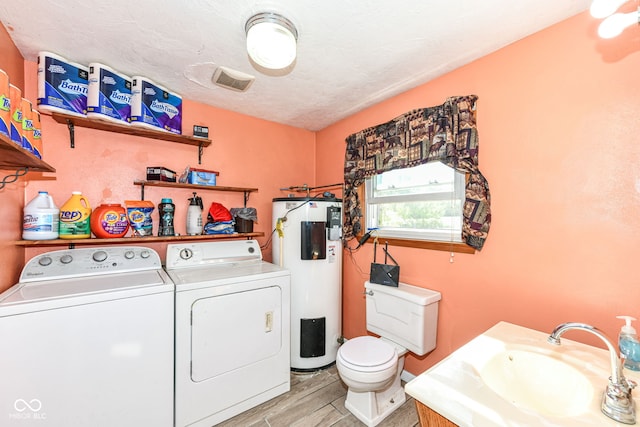 laundry room with a textured ceiling, sink, light hardwood / wood-style flooring, water heater, and washing machine and dryer