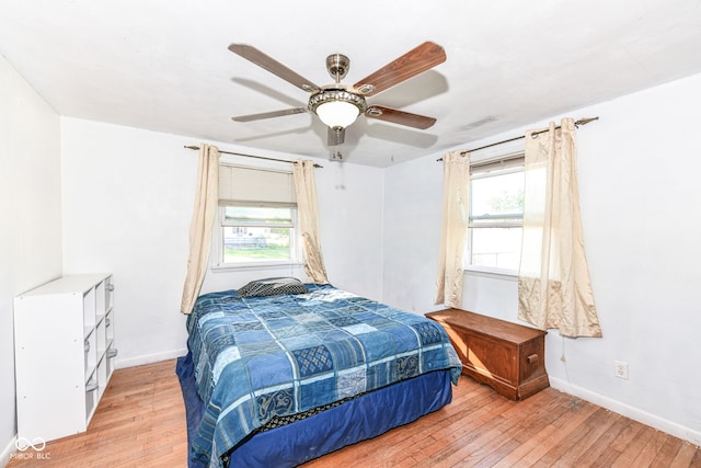 bedroom featuring light hardwood / wood-style flooring, ceiling fan, and multiple windows