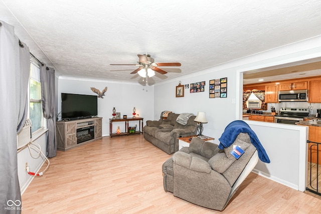 living room featuring ceiling fan, a textured ceiling, and light wood-type flooring