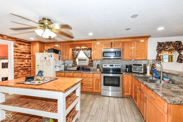 kitchen featuring light wood-type flooring, a textured ceiling, sink, backsplash, and appliances with stainless steel finishes