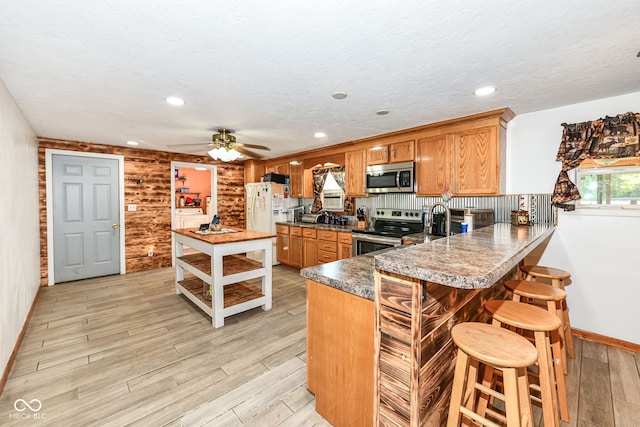 kitchen featuring light hardwood / wood-style flooring, a breakfast bar, kitchen peninsula, and appliances with stainless steel finishes