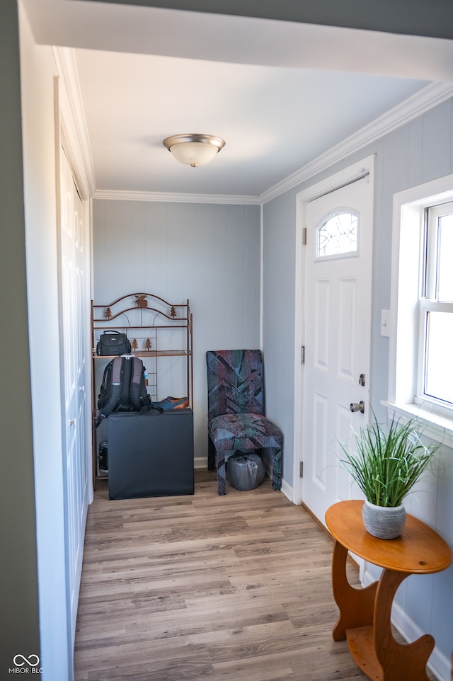 entrance foyer with ornamental molding and light hardwood / wood-style flooring