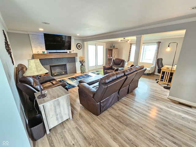 living room featuring decorative columns, ornamental molding, a fireplace, and light hardwood / wood-style flooring