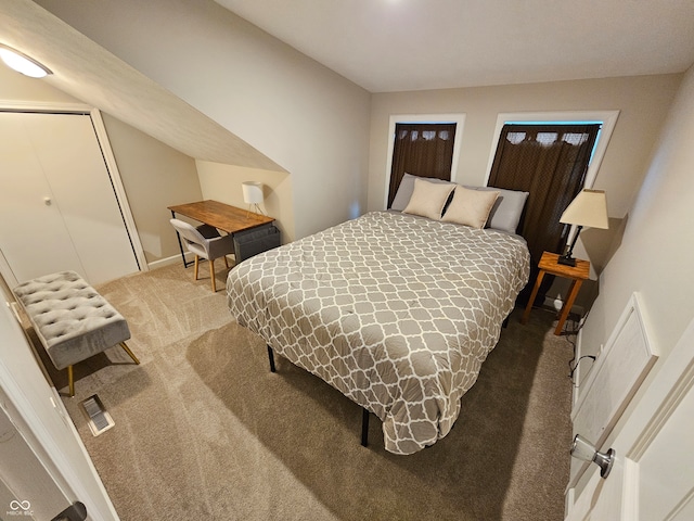 bedroom with vaulted ceiling, carpet floors, and a closet