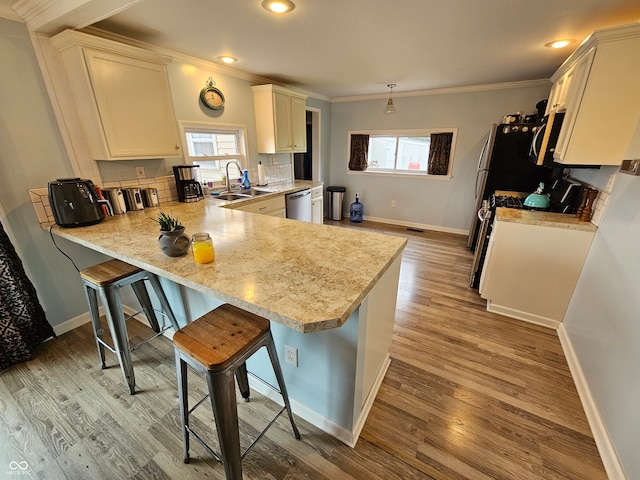 kitchen featuring pendant lighting, sink, a breakfast bar area, stainless steel dishwasher, and kitchen peninsula