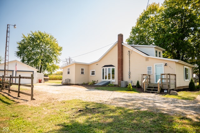 rear view of property featuring cooling unit, a garage, an outdoor structure, and a yard