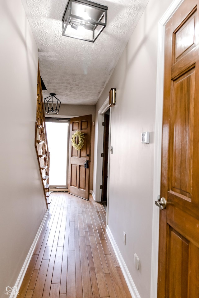 hallway featuring light hardwood / wood-style flooring and a textured ceiling