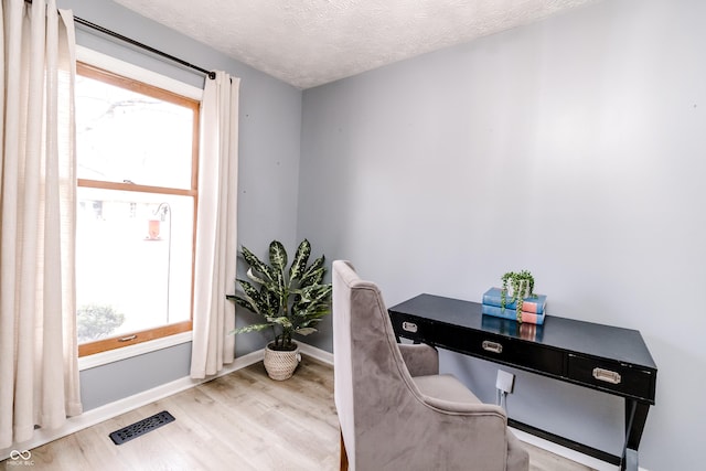 office area with light hardwood / wood-style floors and a textured ceiling