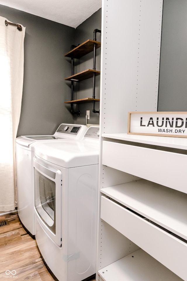 clothes washing area featuring light hardwood / wood-style flooring and washer and clothes dryer