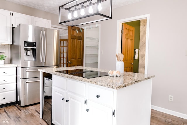 kitchen with stainless steel refrigerator with ice dispenser, light stone counters, white cabinets, a kitchen island, and black electric cooktop