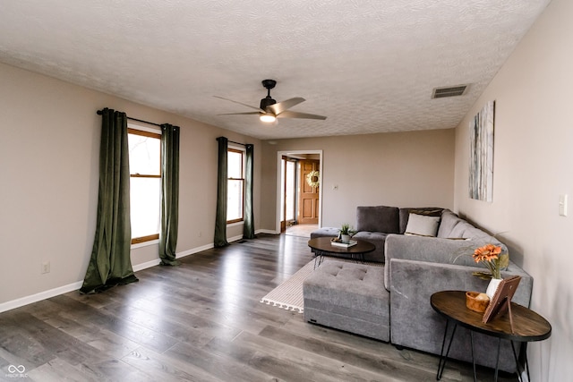 living room with ceiling fan, dark hardwood / wood-style floors, and a textured ceiling