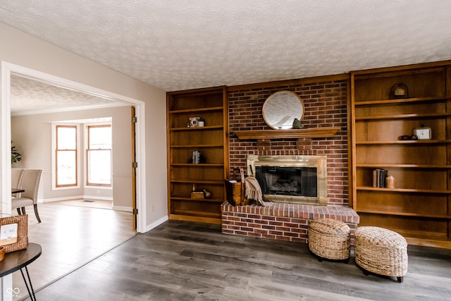 living room featuring a brick fireplace, a textured ceiling, dark hardwood / wood-style flooring, and built in shelves