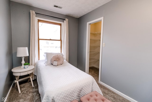 carpeted bedroom with a spacious closet and a textured ceiling