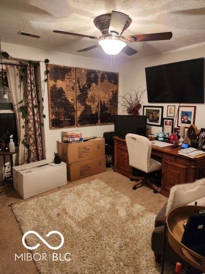 carpeted office featuring a textured ceiling, ceiling fan, and built in desk