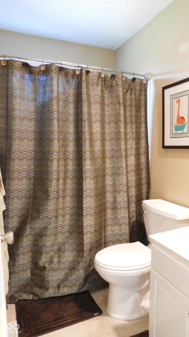 bathroom featuring curtained shower, vanity, toilet, and tile patterned floors