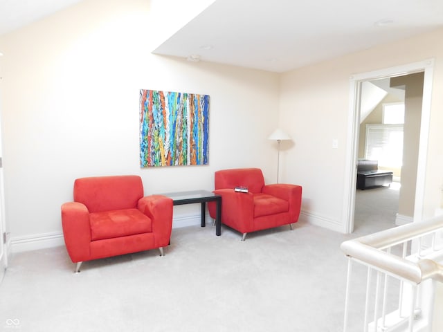 sitting room with vaulted ceiling and light colored carpet