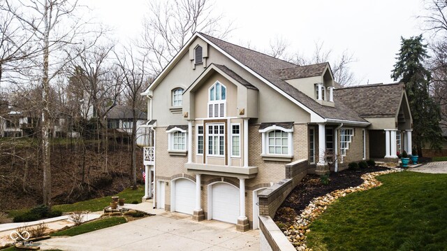 10781 Cedar Ridge Ln, Brownsburg, IN 46278 - view of front facade featuring stucco siding, brick siding, an attached garage, a shingled roof, and driveway