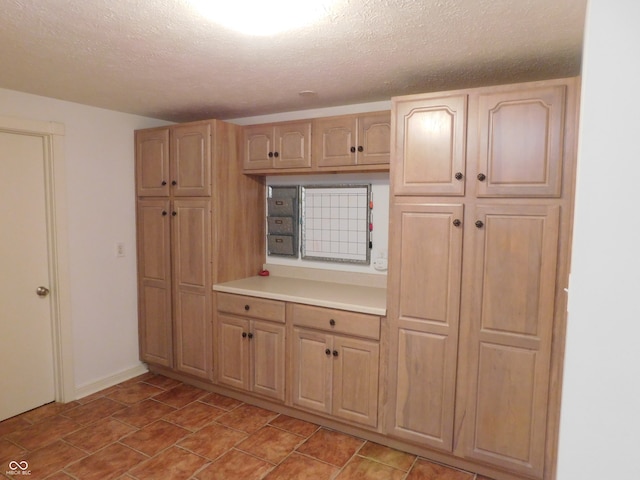 kitchen with a textured ceiling and light brown cabinets