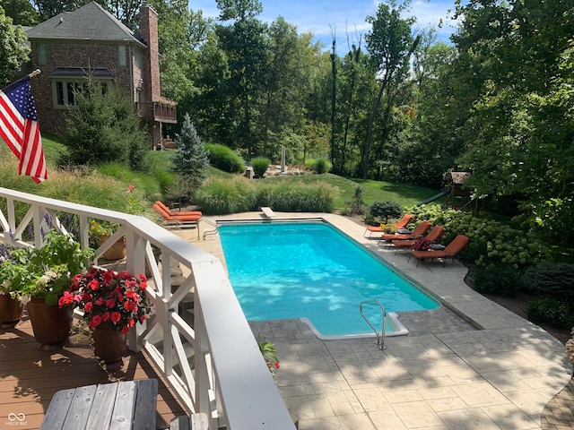 view of swimming pool featuring a deck, a diving board, and a patio area