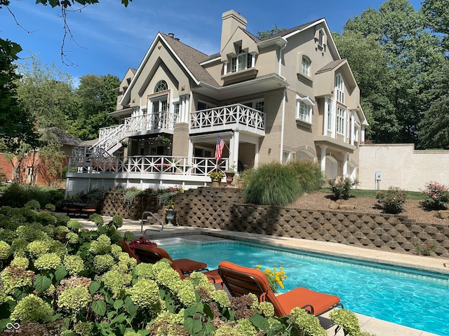 back of property with a balcony and a fenced in pool