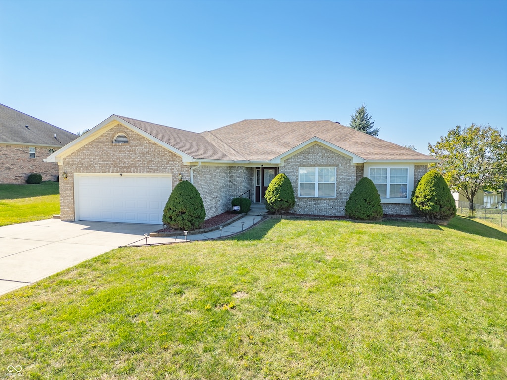 single story home featuring a garage and a front lawn