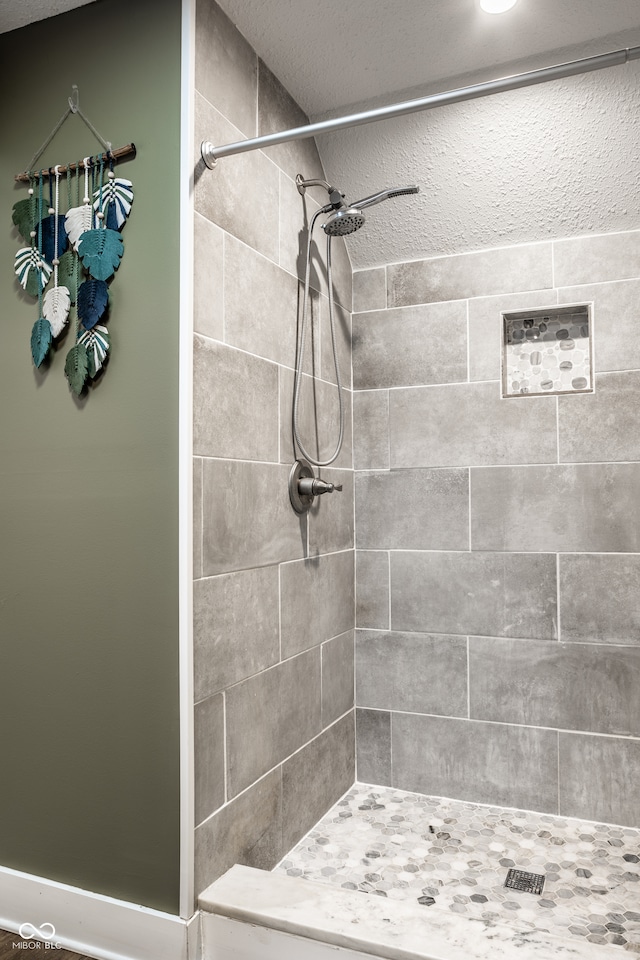 bathroom with a textured ceiling and a tile shower