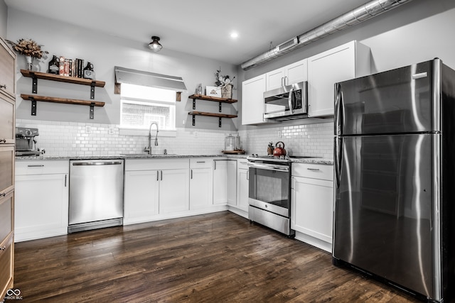 kitchen with light stone counters, sink, white cabinetry, stainless steel appliances, and dark hardwood / wood-style floors