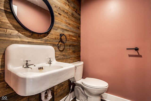 bathroom featuring wood walls and toilet