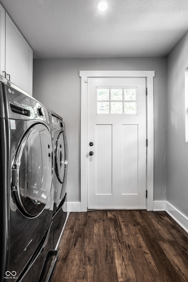 laundry room with a textured ceiling, separate washer and dryer, dark hardwood / wood-style floors, and cabinets