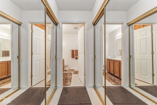 hallway featuring a textured ceiling and light colored carpet