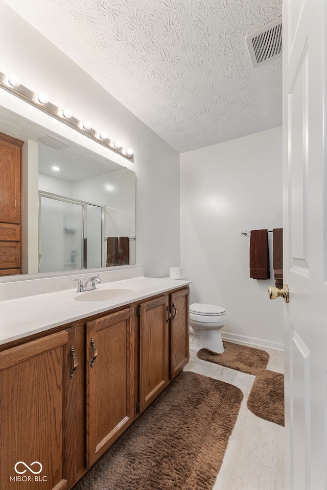 bathroom featuring a textured ceiling, a shower with door, hardwood / wood-style floors, vanity, and toilet