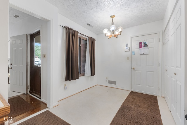 carpeted foyer featuring a textured ceiling and a notable chandelier