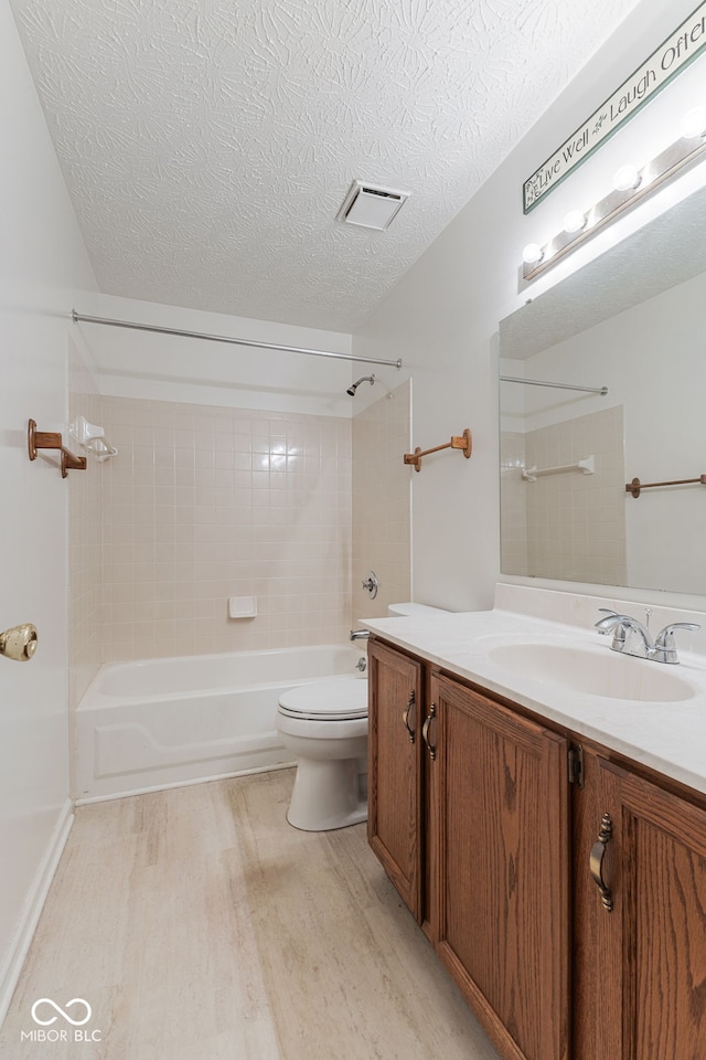 full bathroom with vanity, a textured ceiling, toilet, hardwood / wood-style floors, and tiled shower / bath